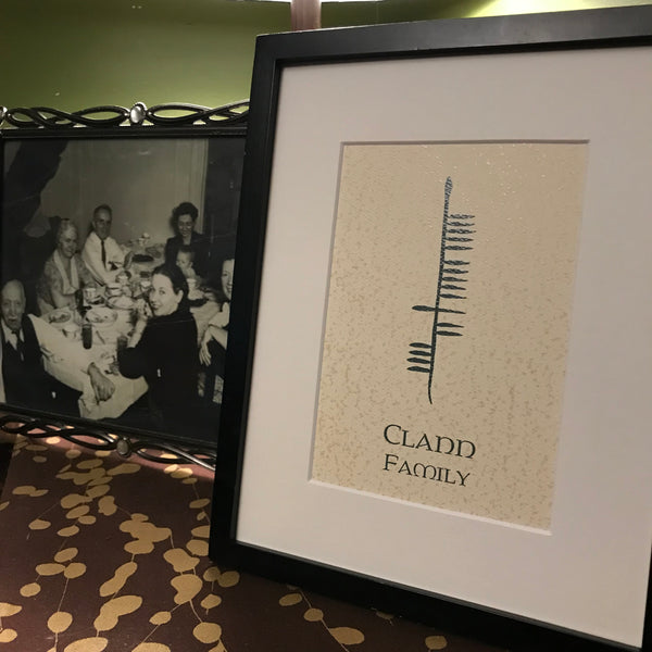 Clann Family Ogham print on table with old photo of people in the background
