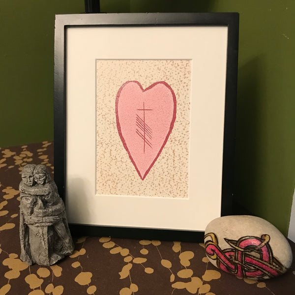 Pink heart with Ogham writing in the middle set up on a table